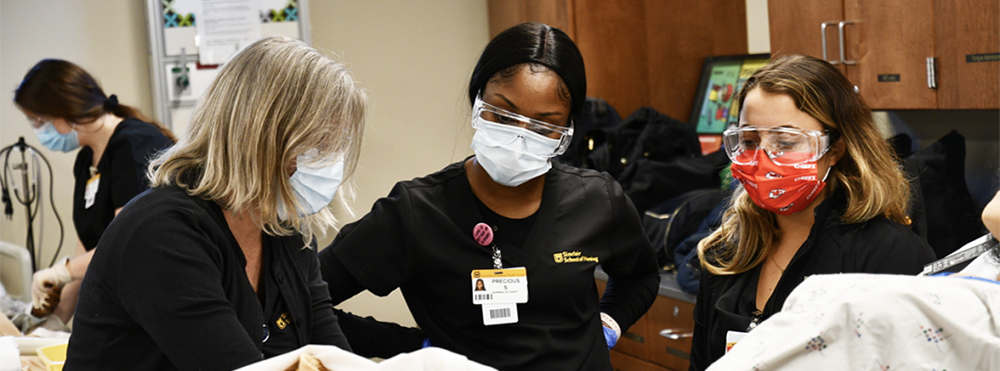 Three nursing students work with hi-fidelity mannequin during cardiac simulation lab.