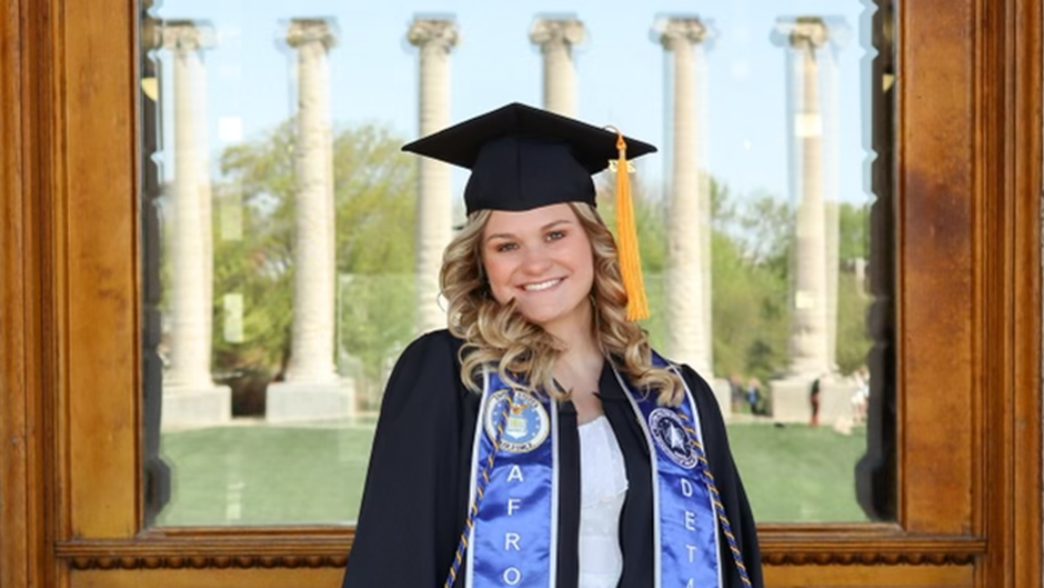 Bailee Hubbard smiles, commencement regalia, Jesse Hall, columns.