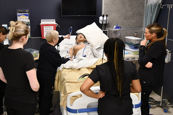 Instructor, students, patient in bed, clinical skills lab