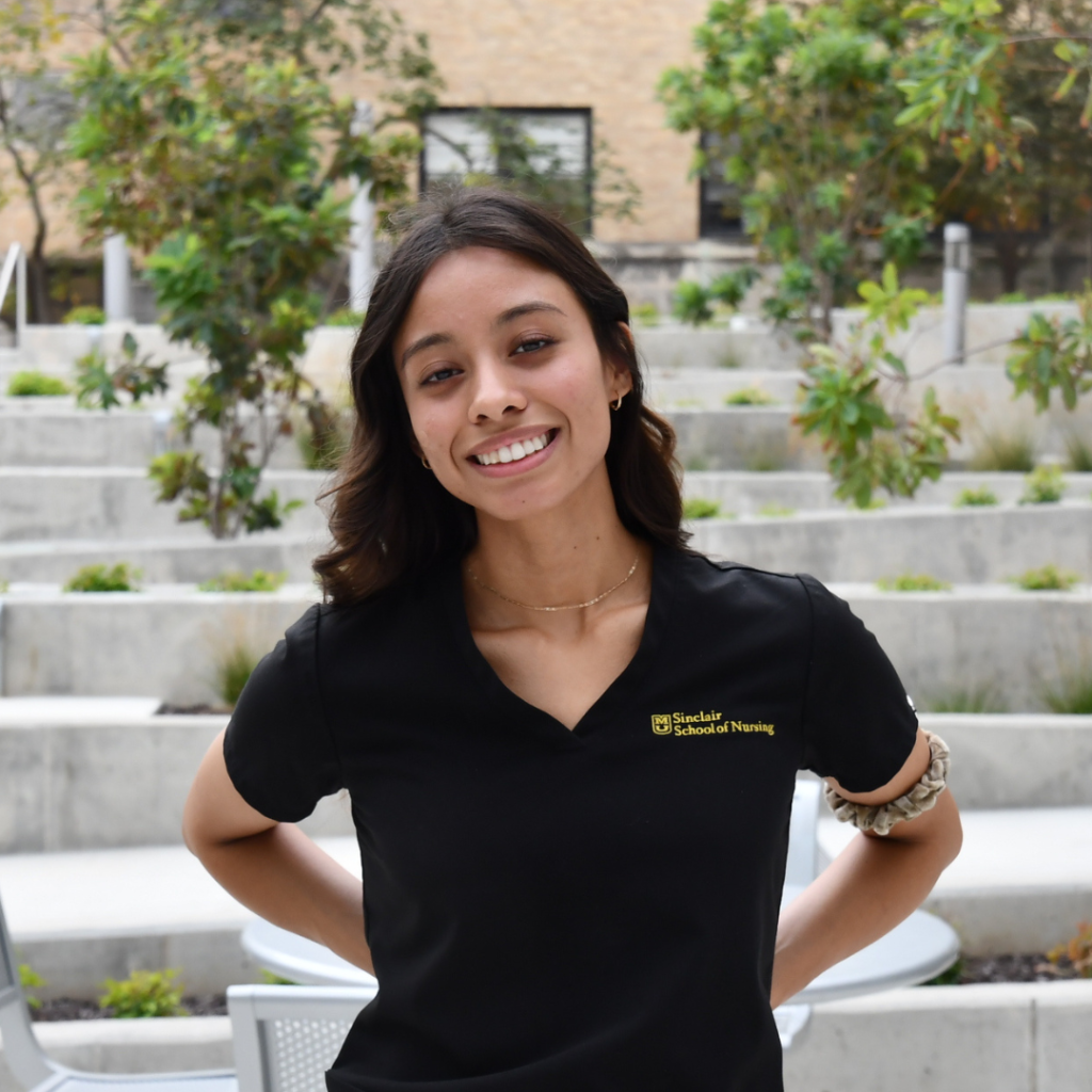 Mena smiles in courtyard.