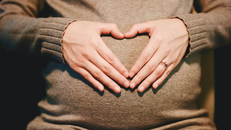 Photo of a pregnant mother with hands in shape of a heart.